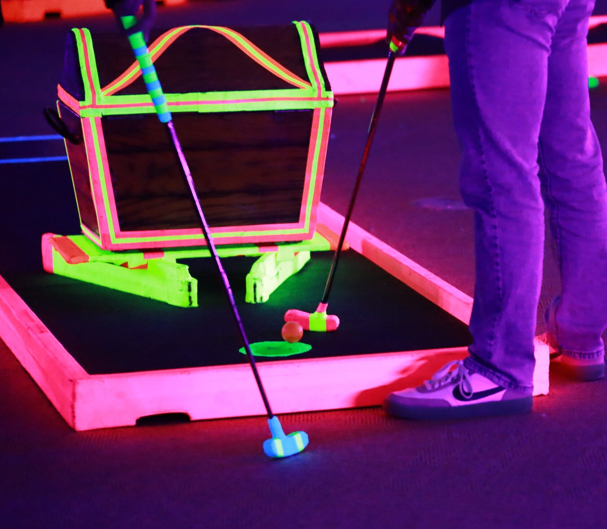 Students playing mini golf at a Neon Night event